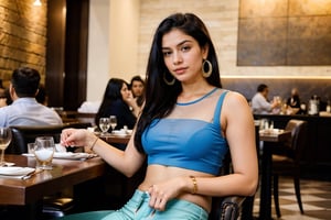 A confident Indian Instagram model sits amidst a luxurious restaurant's daytime ambiance, enjoying warm coffee, surrounded by people. Her long black hair glistens in the radiant glow, wearing stylish transparent light blue top and blue pants, She savors warm coffee with friends, modern earrings catch the light as she turns, 