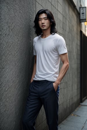 A realistic image of a young Asian man with long, wavy black hair, embodying the influencer persona. He has a slim body, dressed in a trendy outfit featuring trousers, a shirt, and a white t-shirt. The man poses confidently in front of a textured wall on a Seoul street, his gaze fixed on the camera. The composition captures his fashionable ensemble and the urban setting, with natural lighting accentuating the scene's authenticity.