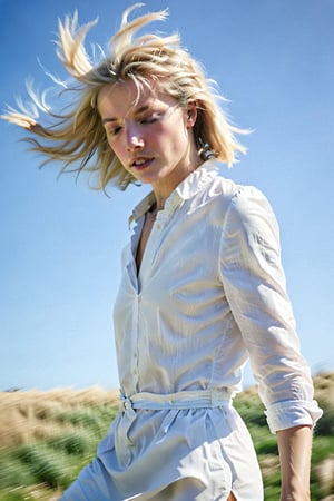 The image presents a woman with blonde hair in motion, suggesting a windy environment. The sky is clear and blue, indicating good weather conditions. The woman's attire is minimalistic and white, which contrasts with the blue of the sky. The overall impression is one of a serene and tranquil setting, with the focus on the woman and her dynamic hair.