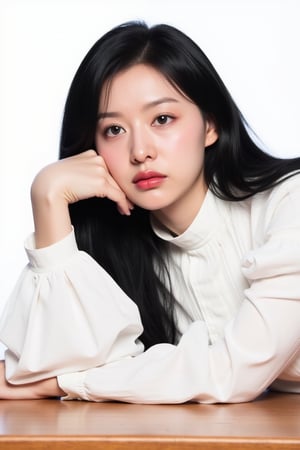 The image is a portrait of a young woman with long black hair. She is wearing a white blouse with a high collar and long sleeves. Her hair is styled in loose waves and she is resting her head on a wooden table. The woman is looking directly at the camera with a serious expression on her face. The background is plain white, making the woman the focal point of the image.