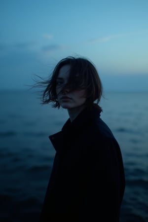 CridLight, 
A portrait of a person, captured in a moody, atmospheric setting. The subject is positioned against a backdrop of a serene seascape, with the ocean meeting the horizon. The sky is painted in a gradient of deep blue to lighter shades, suggesting either dawn or dusk. The person's hair is tousled by the wind, adding a dynamic element to the composition. The individual is dressed in a dark, possibly black, outfit, which contrasts with the lighter background. The overall color palette is dominated by cool blues and blacks, creating a sense of solitude and introspection.