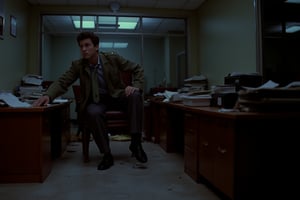 35mm film stock, 50mm f16 lens. Still image from a 1972 psychological horror film. The inside of a generic office building. Our hero, 25 years old, wearing charcoal slacks, a skinny tie, and an olive drab army jacket, is crouching behind a semi-destroyed desk. Most of the lights have failed and the background is very dark. He is terrified. Filmed from waist high, dramatic lighting, deep focus style,Technicolor style