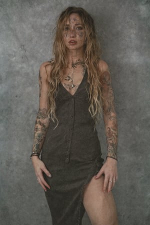 Upper body photo of a 30yo metal woman with very long hair, a cute round face with freckles, tattoos.
She wears a tight fitted sleeveless dress. 