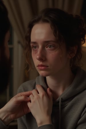 A close-up shot of a young woman's tear-stained face, her eyes welling up with tears as she struggles to hold back sobs. Her boyfriend's hand is seen gently pinching her arm, his expression apologetic yet firm. The dimly lit room casts a warm, intimate glow on the couple's emotional confrontation.