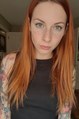 Upper body photo of a 30yo metal woman with very long hair, a cute round face with freckles, tattoos.
She wears a tight fitted sleeveless dress. 