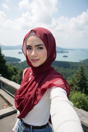 This is a high-resolution photograph featuring a young woman taking a selfie at an elevated viewpoint, likely a lookout or skywalk. The woman is of South Asian descent, with fair skin and a round face adorned with meticulously applied makeup, including bold, winged eyeliner and matte lipstick in a deep red shade. She wears a white, long-sleeve ribbed knit sweater ((extra tight)) and a voluminous, rich red hijab that flows gracefully around her, covering her head and shoulders. 

Her hijab is made of a lightweight, sheer fabric that allows for a soft, delicate texture contrasted against the knit sweater. She has a confident smile and is looking directly at the camera, capturing the moment with her right arm extended.

In the background, the scene extends to a breathtaking panoramic view of lush green forested hills and a vast body of water, likely a sea or lake, under a partly cloudy sky. The horizon is distant, with faint outlines of distant islands and the coastline. The overall mood of the image is serene and picturesque, highlighting both the beauty of nature and the woman's elegant attire.