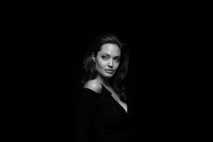 Black and white portrait of Angelina Jolie, dark background, shadow play, soft lighting, cinematic style