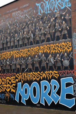 a large graffiti wall, with the artwork of a horde of Norse men with axes and swords with detailed features, other graffiti writings on the same wall