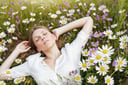 a woman lying in a meadow full off flowers, white theme
