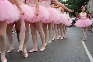 Photo Closeup of a group of woman ballerinas in pink tutus, parading through the street holding AK47s.