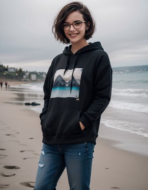Female, Emo hairstyle, short hair, Brunette, Smiling, black hoodie. And jeans, Hands in pockets on beach, hipster black big frame glasses, nose stud 
