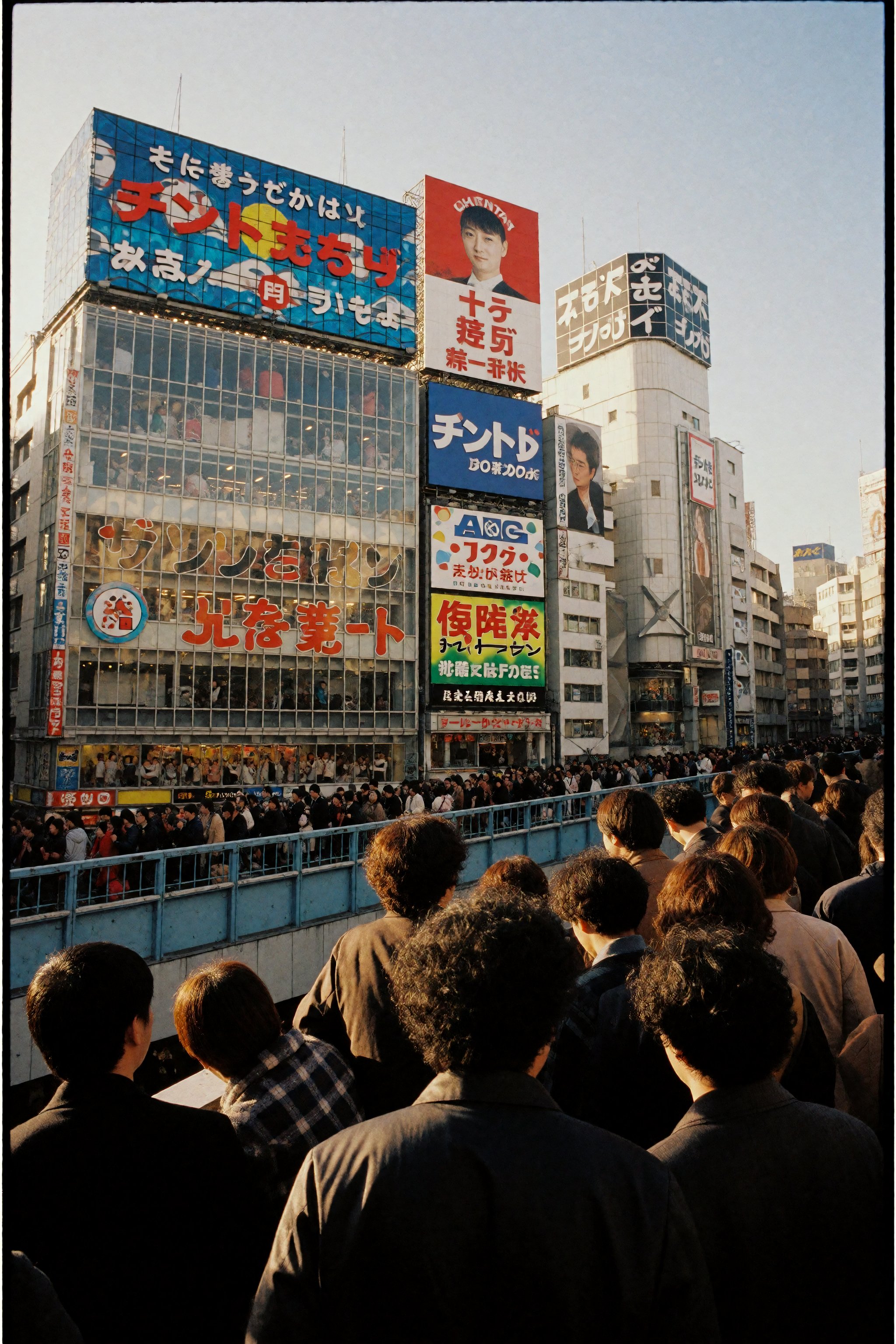 Photograph of a bustling urban Japanese street at sunset,  viewed from behind a crowd of people standing on a raised platf...