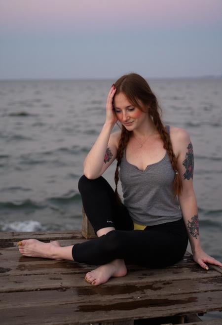Ava Adore sits slumped on weathered wooden planks of an old pier at dusk,  surrounded by murky waters of the Pacific Ocean...