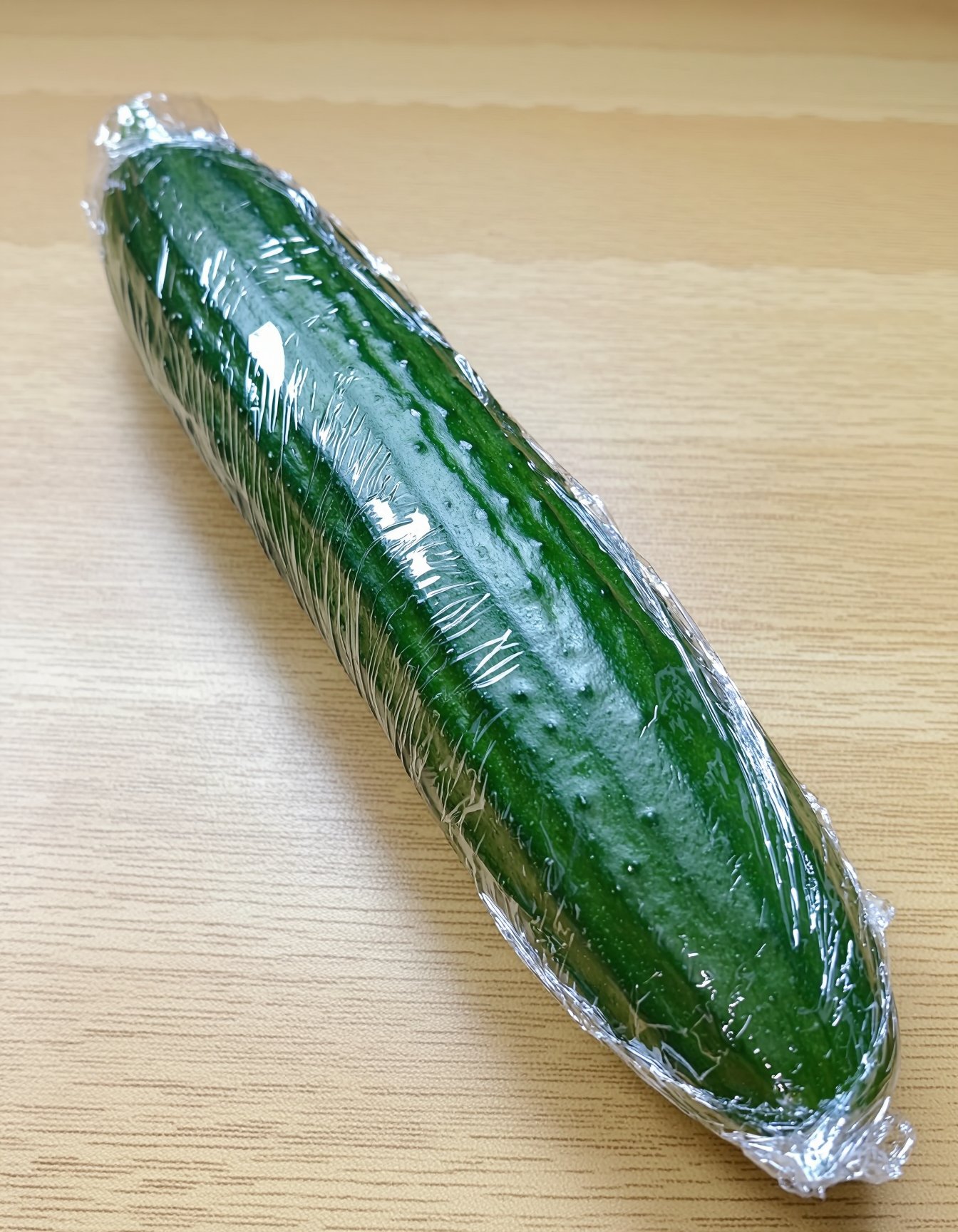 A cucumber sitting on the table wrapped in plastic clingfilm. by user_z on Tensor.Art