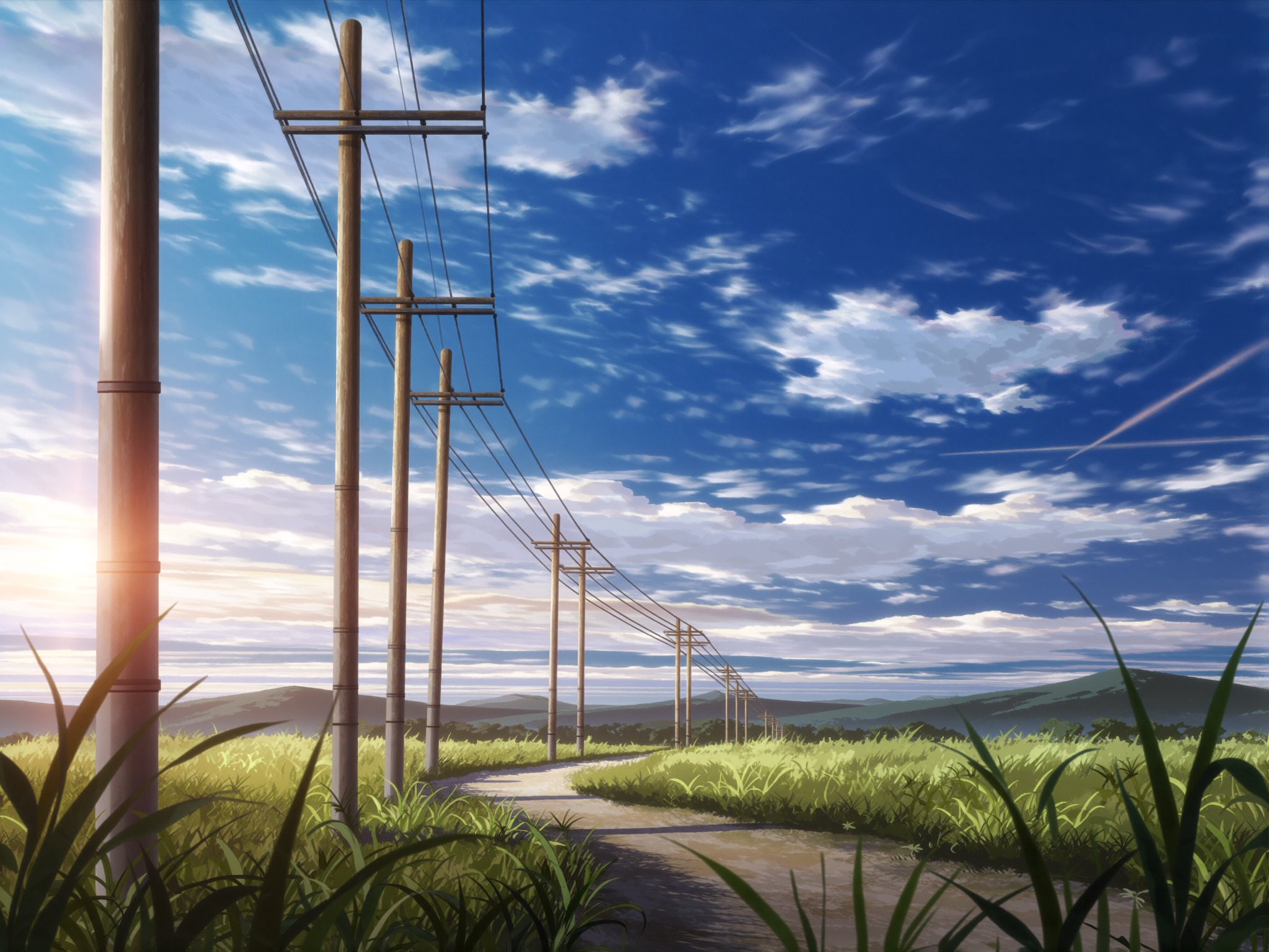 A scenic landscape under a vast blue sky with scattered clouds stretching across the horizon. The sun casts warm rays thro...