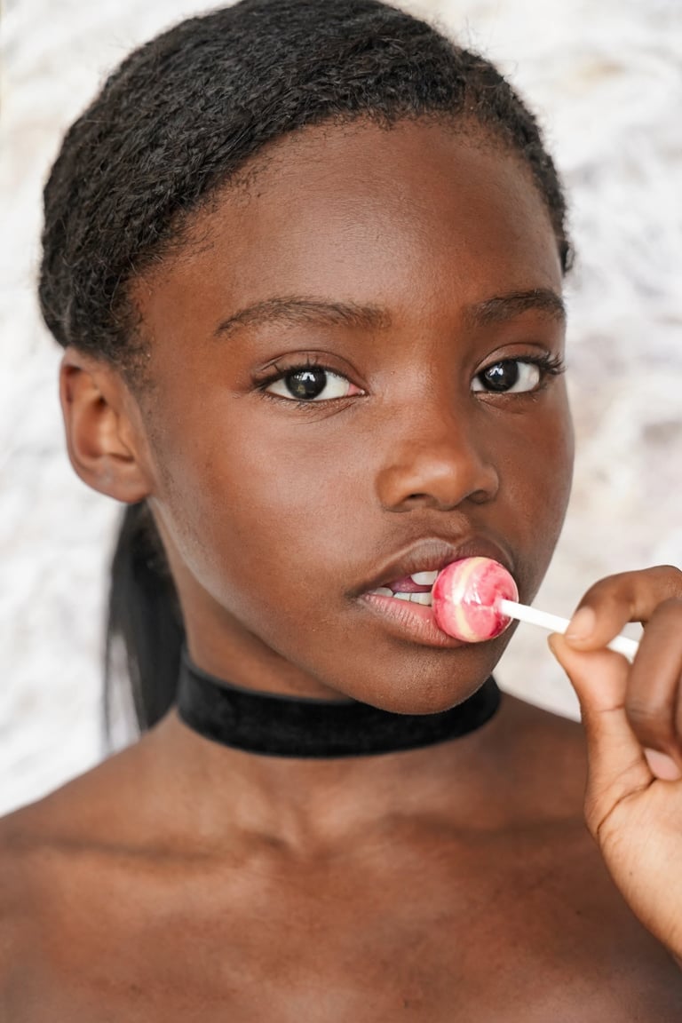 Close-up portrait of HassieHotkins. She is wearing a black choker,  her hair is in a ponytail,  and she is holding a pink...
