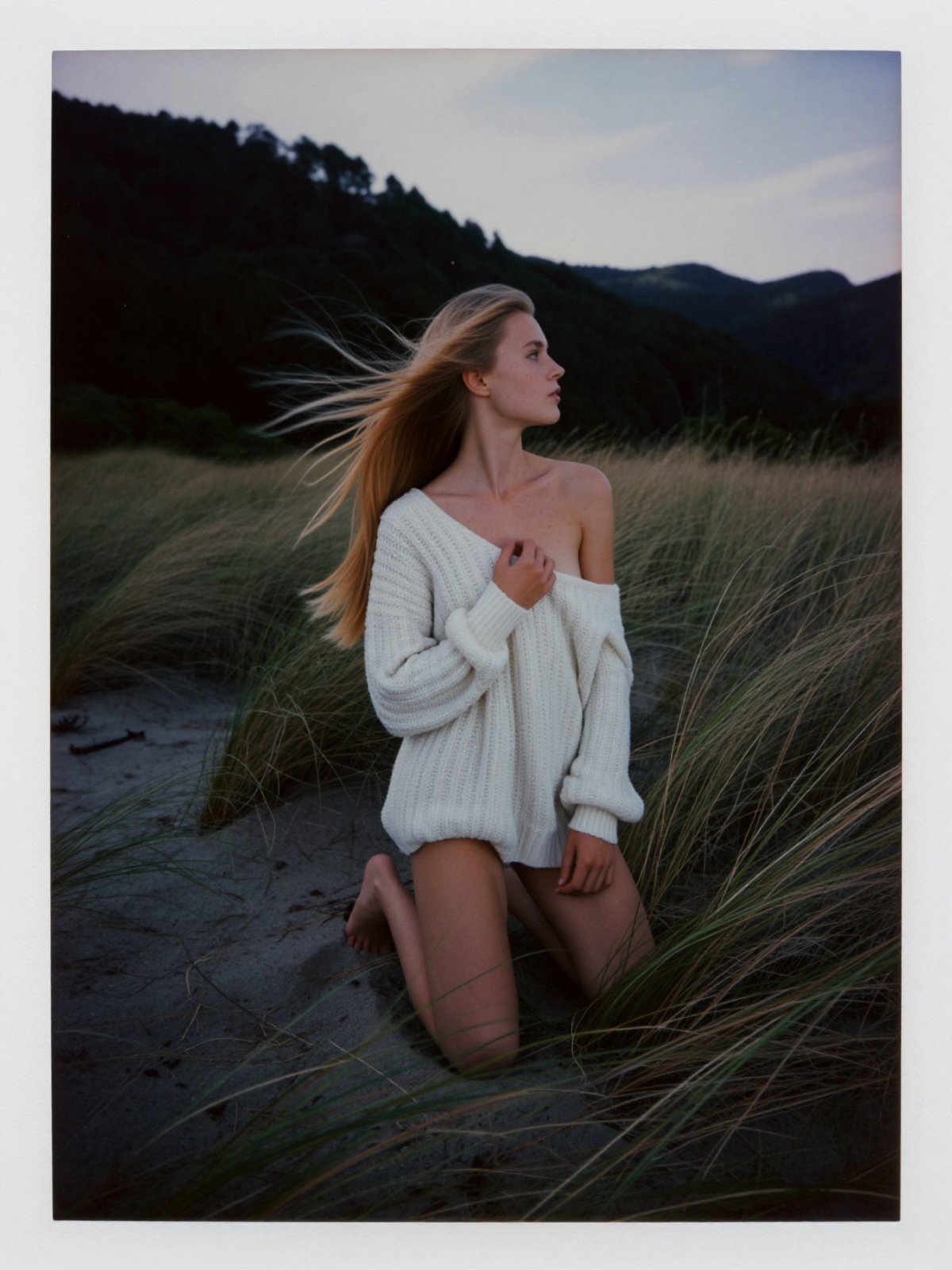 An authentic amateur analogue photograph of a young woman in her early twenties kneeling in windswept coastal dune grass a...