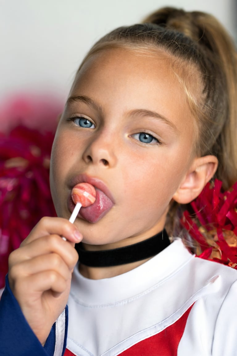 Close-up portrait of a young girl,  Snoomer_de_Summ. She is wearing a cheerleader uniform and a choker,  her hair is in a...