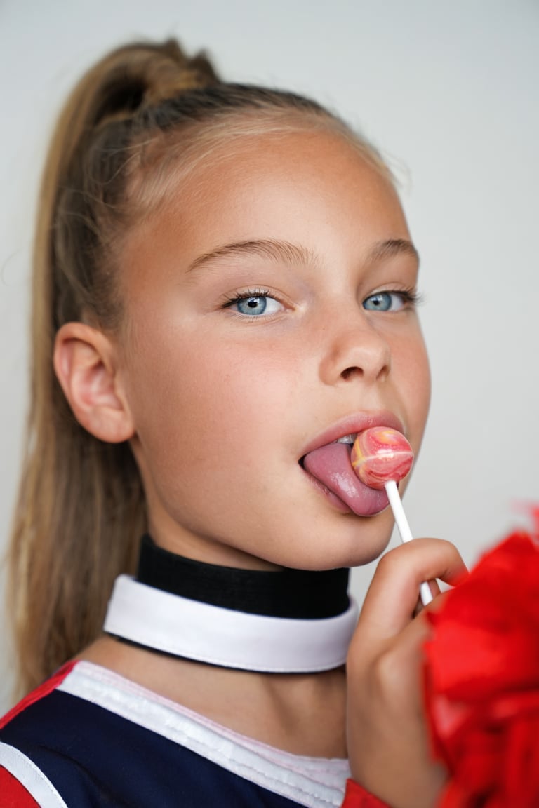 Close-up portrait of a young girl,  Snoomer_de_Summ. She is wearing a cheerleader uniform and a choker,  her hair is in a...