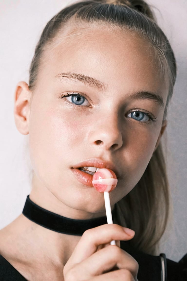 Close-up portrait of Snoomer_de_Summ. She is wearing a black choker,  her hair is in a ponytail,  and she is holding a pin...