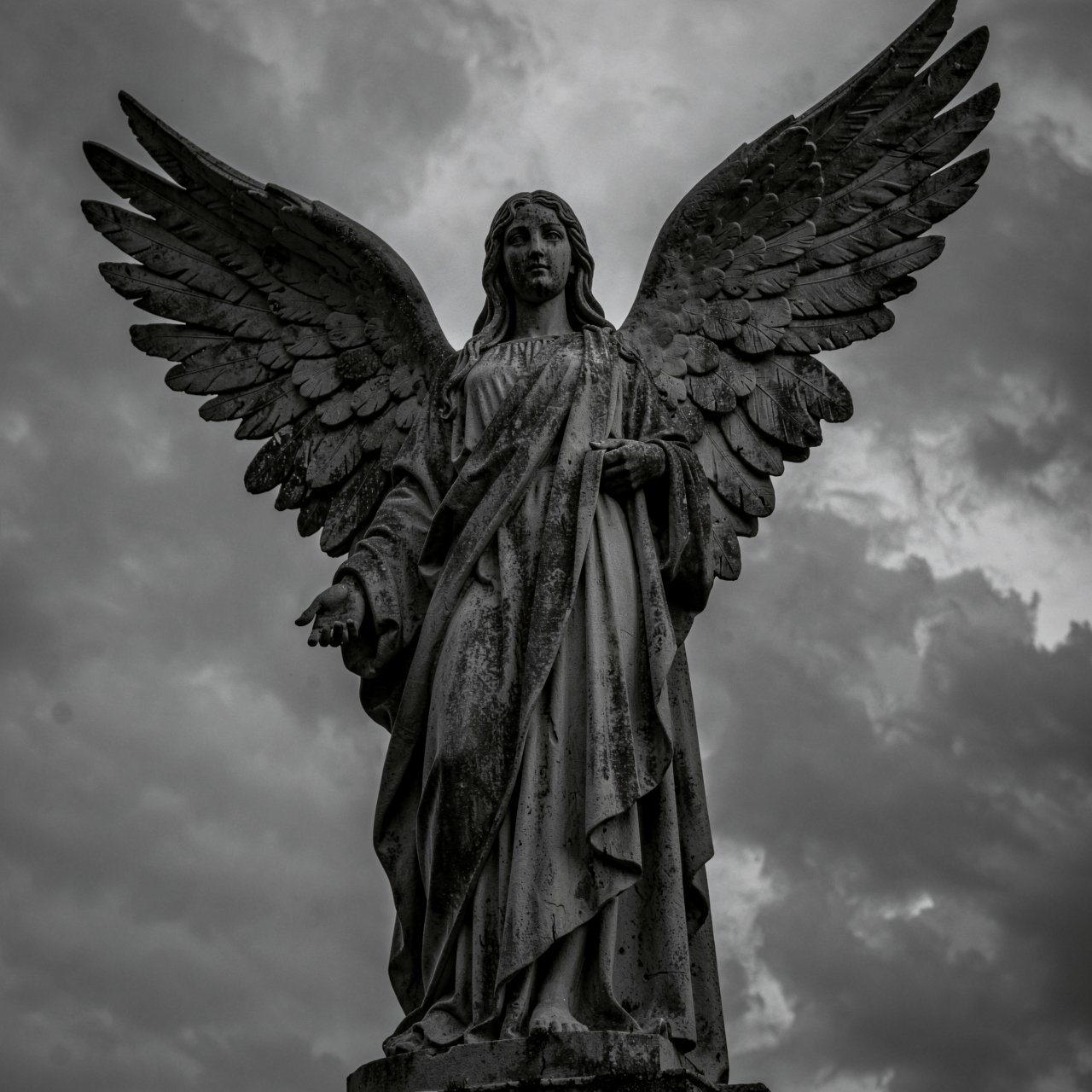 HFMAXDARK,  A weathered stone statue of an angel is captured from a dramatic low-angle perspective against a dark,  overca...