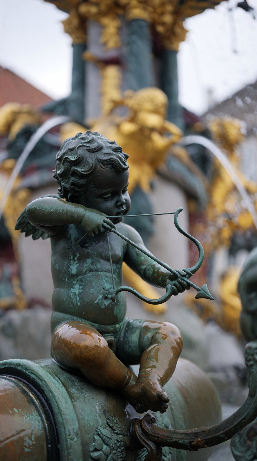 a weathered bronze cherub statue,  patinated green with age,  sits perched atop a curved pipe in the foreground by patrik...