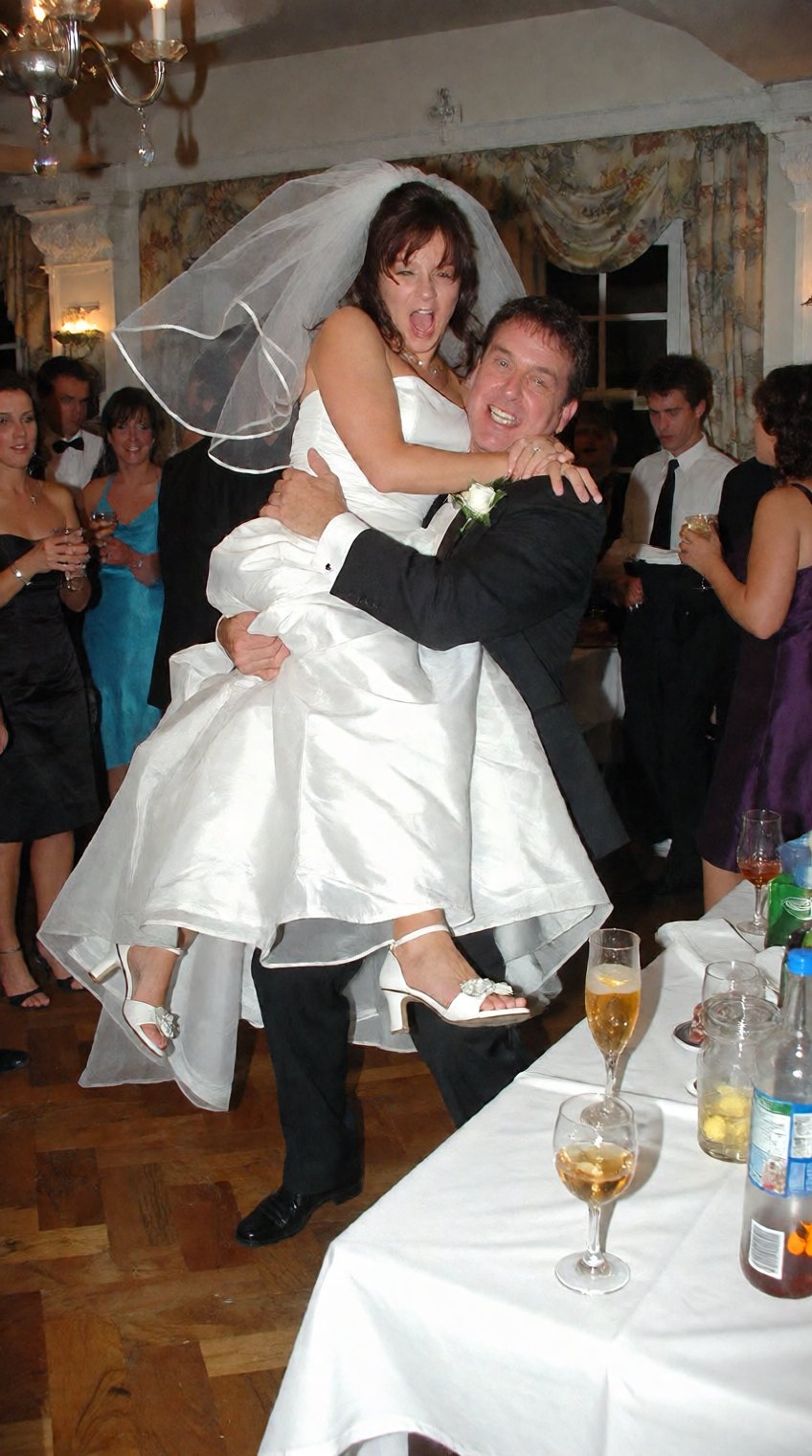 A funny,  candid 2000s digicam photo capturing a chaotic moment at a crowded wedding reception dancefloor. A tipsy middle-...