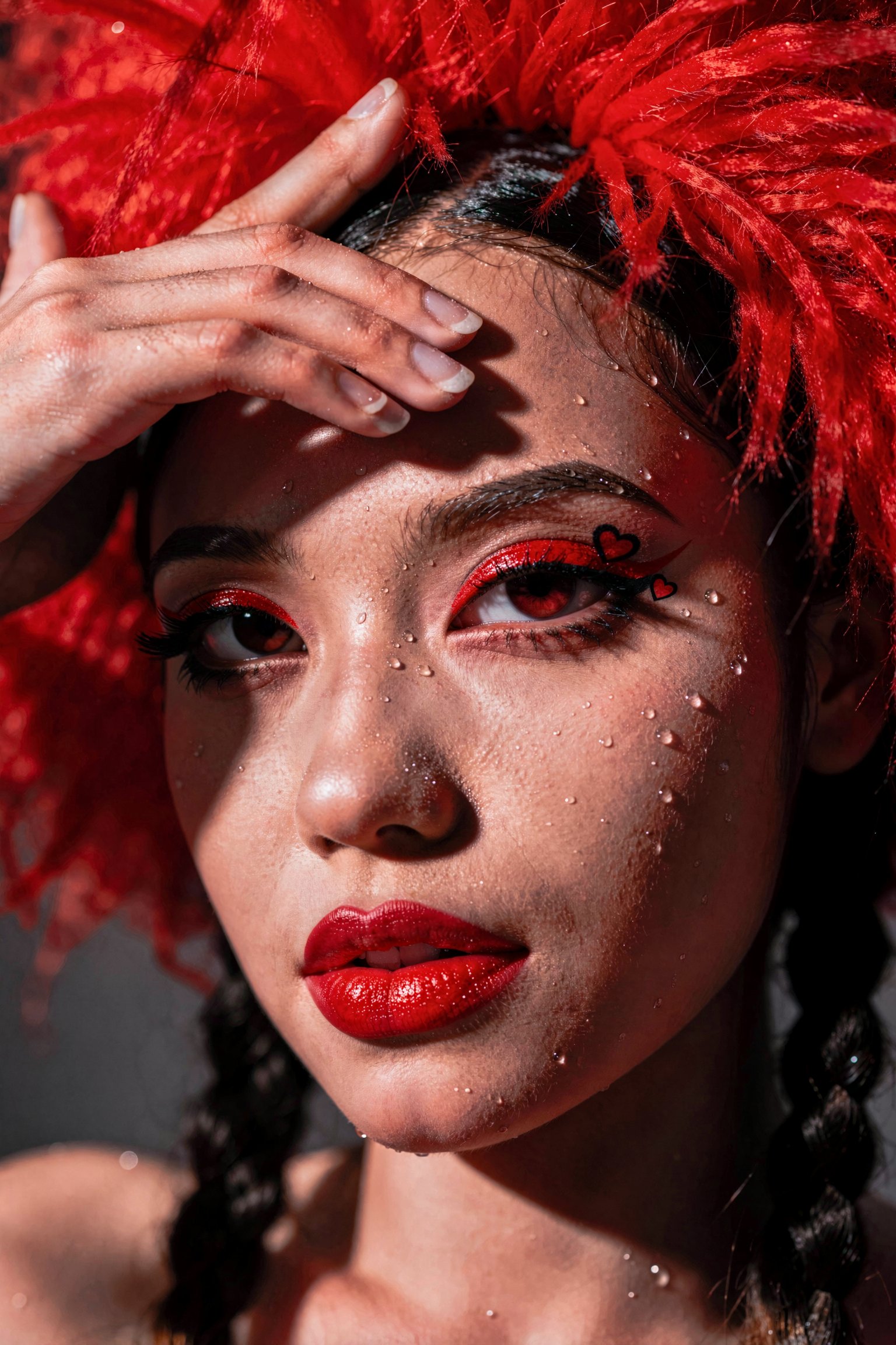 Close-up editorial portrait of a woman with vibrant ruby red lipstick and graphic red eyeliner detailed with tiny hearts....
