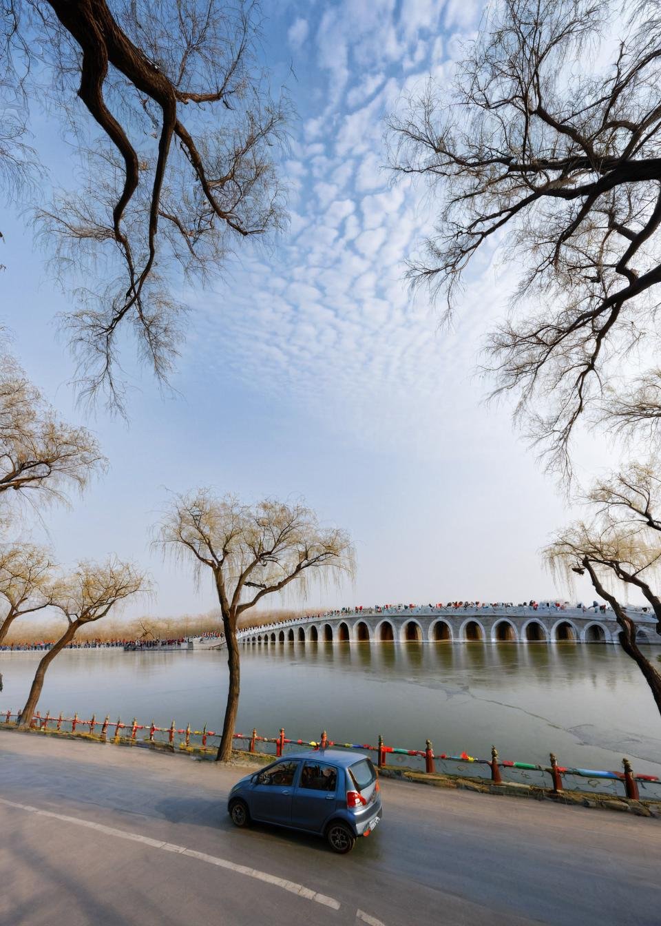 <lora:颐和园:1>,The Summer Palace, tree, scenery, bridge, outdoors, bare tree, multiple boys, car, ground vehicle, sky, motor vehicle, water, building, river, day, road, street, city, dutch angle, real world location, power lines, 6+boys, cloud, masterpiece, best quality,