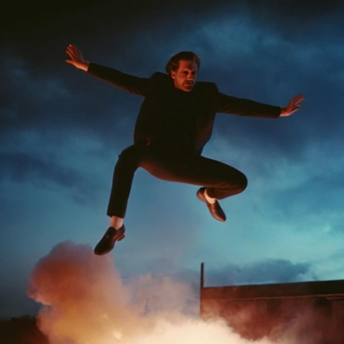 cinematic film still of 1980's a man is jumping in the air on the rood top with smoke and night sky in the back In the gra...