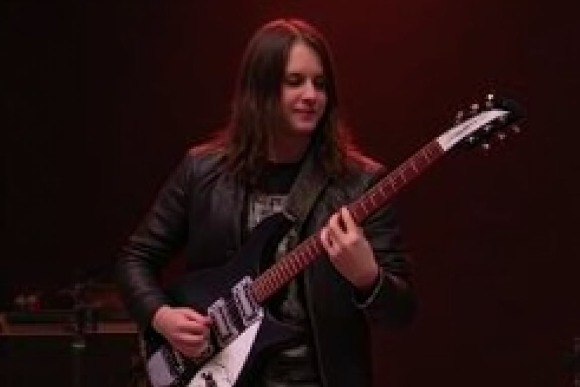 1boy,solo,front view,half body, standing,Rickenbacker,electric guitar, playing guitar in a nightcub on stage, long hair, black leather jacket, van dyke