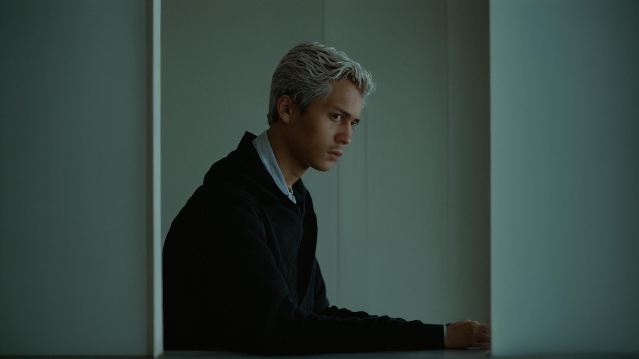 cinematic film still of  <lora:Ron Fricke style v2:0.9>a man leaning out of a window with his hand on his chin,solo,short hair,long sleeves,1boy,white hair,male focus,indoors,dark skin,hood,window,profile,hood down,head rest,lamp,wall , realistic, realism, movie still, film grain, kodak film, film contrast, film color, cinematography, documentary, photography, 70 mm film, 65 mm film, Todd-AO, Todd-AO 35, 8K resolution, Ron Fricke film director style, Ron Fricke film directing style, Ron Fricke style, shallow depth of field, vignette, highly detailed, high budget, bokeh, cinemascope, moody, epic, gorgeous, film grain, grainy