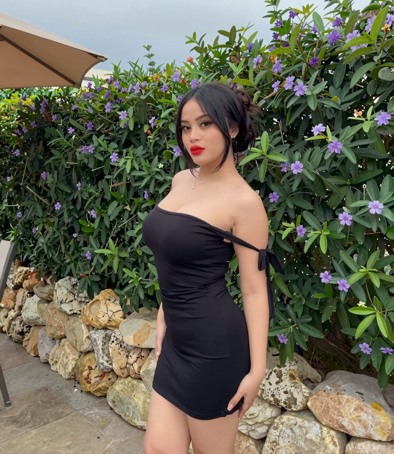 A young woman with dark hair gathered into a bun stands outdoors,  posing for a portrait,  looking over her shoulder at vi...
