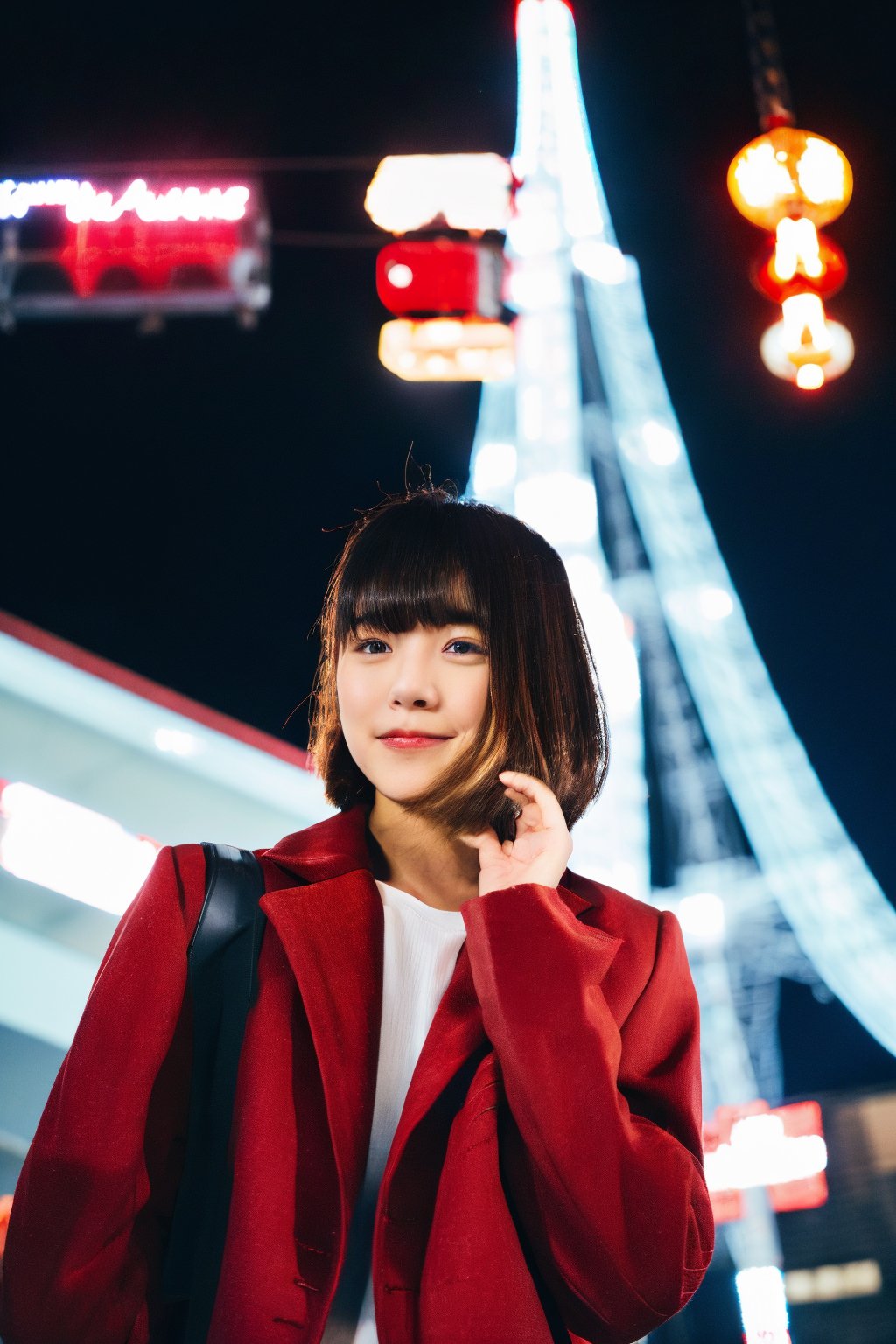 A young Asian woman, short hair, wearing a red jacket and a white t-shirt with Japanese text, necklace, standing on a Tokyo street at night, with Tokyo Tower in the background, illuminated city lights, red lanterns, urban style, night photography, candid pose, low angle shot, with a hint of film grain.

,fujifilm