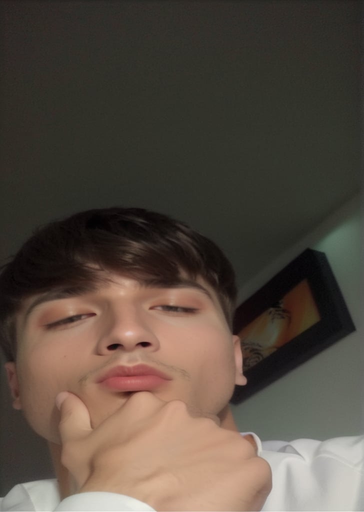  close-up selfie of ((ultra pretty, beautiful, handsome man)) 23 years old, with short, chestnut hair, light skin. He is wearing a white shirt and has a contemplative audacious expression, vibrant performance. with his hand resting on his chin. The background is dimly lit, showing part of a wall with a framed picture that has abstract patterns in black, white, and orange colors. The overall lighting is low, creating a slightly shadowed effect on the subject's face. Skin with a hyperrealistic texture, perfect symmetry, high resolution.