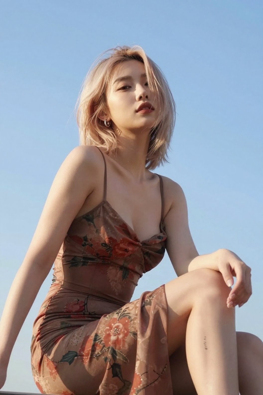 The image shows a asian girl sitting outdoors,  with their body slightly turned to the side. They are wearing a sleeveless...