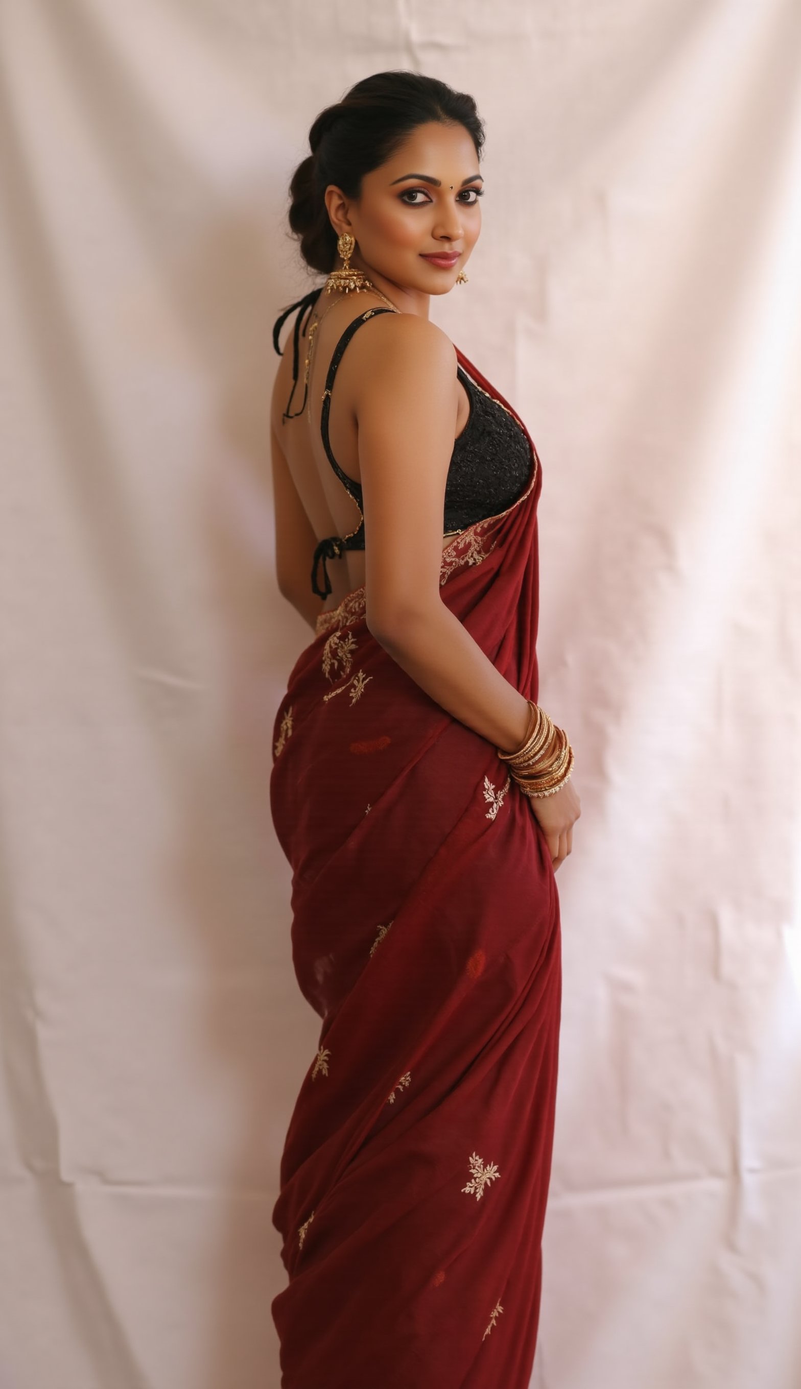 a medium-sized sexy indian woman stands in sidewise in front of a white curtain. She is dressed in a black sleeveless blouse with a maroon sari adorned with gold embroidery. Her hair is pulled back in a ponytail, and she is adorned with a pair of dangling earrings. Her bangles are gold, adding a touch of contrast to her dress. The backdrop is a stark white, creating a stark contrast to the woman's outfit.,photorealistic, Warm Lighting, Looking towards the viewer in a  sensual way, kadvani