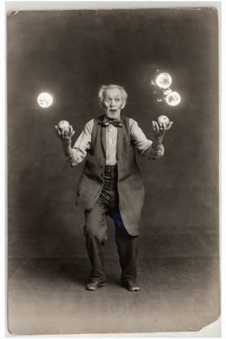 photograph of an old man juggling five balls of fire