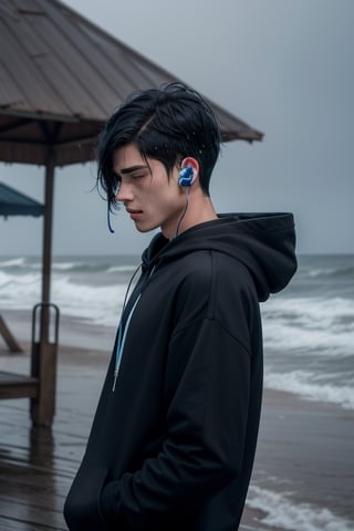 a teenage boy standing under the rain drenched near the ocean, sad and crying, wearing a black hoodie on his head with earphones in his ears. has black and blue hair