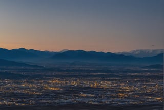 A dense layer of blue clouds illuminated in royalblue from above, a small golden sun, light gray mountains in the distance on the horizon among which power plants and industrial buildings can be seen, closer gray mountains on the horizon among which power plants and industrial buildings can be seen, black mountains on the horizon among which power plants and industrial buildings can be seen,