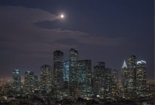 night, dark-orange cloud lumened by city, bright moon, dark-gray-purple sky; sky scrapers square and rectangular skyscrapers with white frequent square windows, shades of skyscraper windows: dark blue, dark turquoise. The roofs of skyscrapers from dark squares or illuminated with a dim blue border,