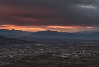 The image depicts a dramatic and industrial landscape. A thick layer of gray clouds dominates the sky, illuminated in a deep red hue from above. Amidst the clouds, a small golden sun peeks out, adding a touch of warmth to the otherwise gloomy atmosphere. In the distance, on the horizon, a range of gray mountains stretches across the landscape. Among these mountains, power plants and industrial buildings can be seen, their structures blending into the rugged terrain. Closer to the foreground, the mountains take on a darker tone, gradually transitioning to black mountains that loom in the distance. These black mountains are also dotted with power plants and industrial buildings, casting long shadows in the fading light.