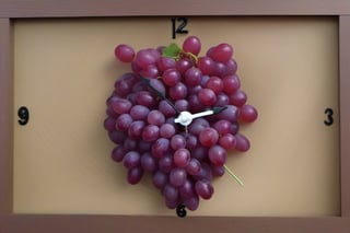 a mechanic clock with one single grain of grape in each hour