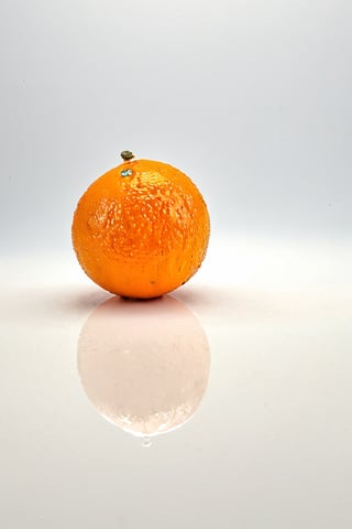 An orange on a white table, studio photography, minimalist background, (best quality, HDR, ultra-detailed), vivid colors, soft lighting.