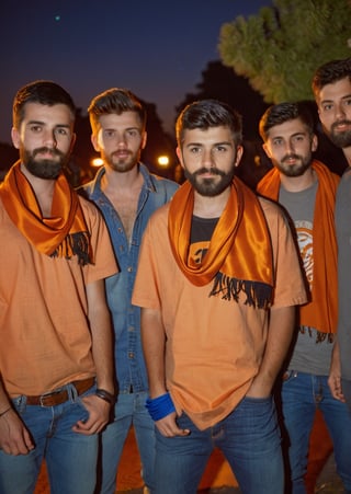 Amateur Cellphone photography photo of a group of boys wearing random cloth, tshirt, shirt, jeans, 17 years old, beard, Short beard, black beard, hair, hairstyle, long quiff hair, cover shoulder of a orange stole of all boy, all boys looking at viewer, texture, hyper realistic, detailed, Night, lighting, outdoor, club 