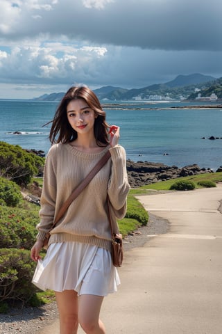 The photo shows a young woman standing on a rocky beach.  The composition of the image is casual and candid.  The subject wore a beige sweater and a white skirt, showing off a sexy and charming smile.  Embodying a feeling of happiness and freedom.  She is carrying a brown cross-body bag.  The background includes a tranquil coastal landscape, a rocky shoreline, calm ocean waves, and distant forested hills under a partially cloudy sky.  There is a walking path with stone walls on the right side of the image, indicating a coastal path or promenade.  The overall mood is relaxed and cheerful.