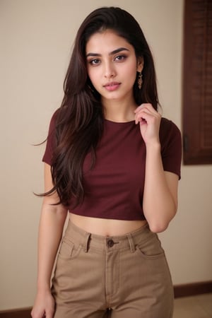 lovely cute young attractive Indian girl, a gorgeous actress,  cute,  an Instagram model, relaxed, with a medium complexion and chestnut-colored hair styled in a casual updo with loose strands around her face. She has a natural makeup look with defined eyes and a neutral lip color. She is wearing a fitted, cropped burgundy T-shirt with short sleeves and high-waisted black pants with distinctive button details. She stands confidently, with one hand on her hip and the other gently touching her pants. The lighting is soft and frontal, highlighting her features and the texture of her clothing against a muted dark background.